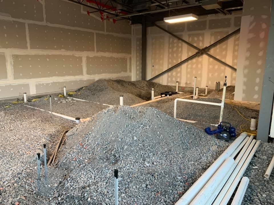 PVC drain and vent pipes roughed in on a gravel base before a concrete floor is poured