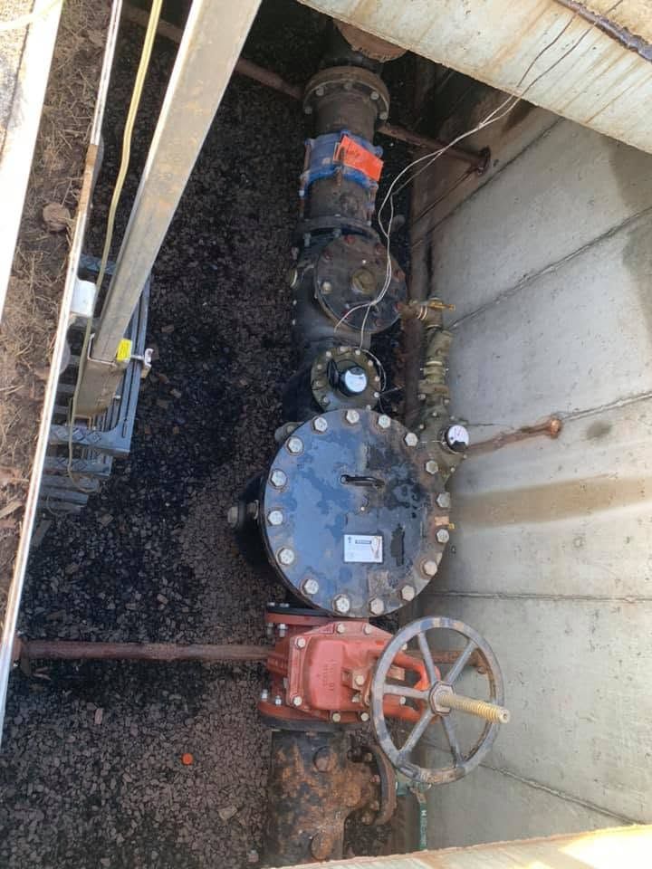 Large water service line in an underground vault with a backflow preventer, meter and red gate valve